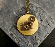 A detailed antiqued brass plated camera on a vintage brass plated locket.  Locket opens with two spaces. Details: Necklace measures 26 inches Locket measures 32mm in diameter Locket is real vintage, each will have its own patina Chain is plated antiqued brass Thank you for shopping Delicate Industry :) Antique Gold Retro Jewelry For Gifts, Retro Antique Finish Jewelry For Gift, Antique Finish Retro Jewelry As Gift, Antique Finish Retro Jewelry For Gifts, Camera Necklace, Unique Christmas Gift, Photographer Gifts, Idea Gift, Real Vintage