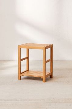 a small wooden table sitting on top of a hard wood floor next to a white wall