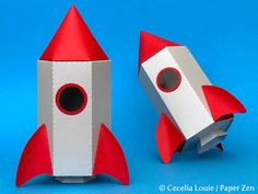 an origami model of a rocket ship and a paper roll on a blue background