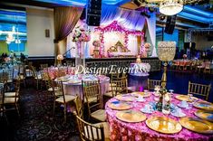 a banquet hall with tables and chairs set up for a formal function, decorated in pink and gold