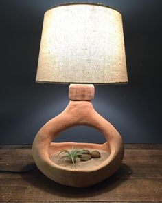 a lamp that is sitting on top of a table with a potted plant in it