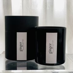 two black candles sitting next to each other on a glass shelf in front of a window