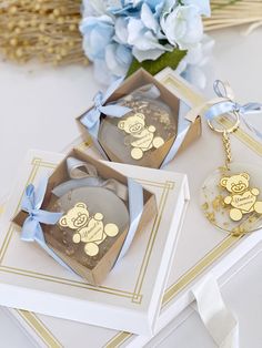 two boxes with key chains in them sitting on a table next to blue and white flowers