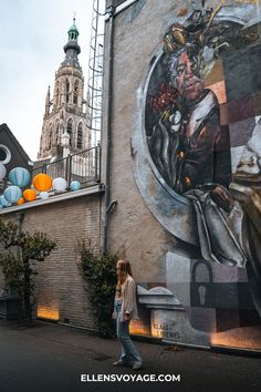 a woman walking past a large painting on the side of a building