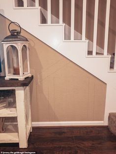 a white lantern sitting on top of a wooden table next to a stair case in a house