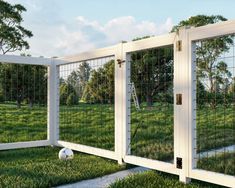 a white fenced in area with grass and a ball on the ground