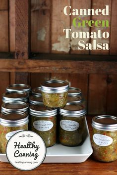 canned green tomato salsa in mason jars on a white platter with the words healthy canning