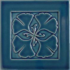 a blue tile with a flower in the center and an intricate design on it's side