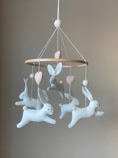 a mobile with three white rabbits hanging from it's sides and hearts on the strings