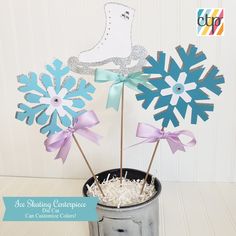 a tin can filled with cupcake toppers and snowflakes on sticks