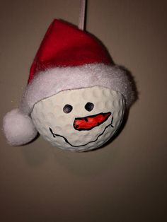 a golf ball with a santa hat on it's head hanging from a string