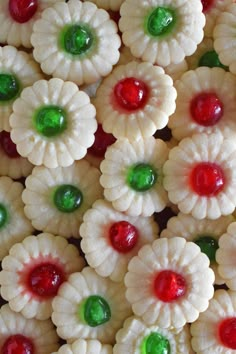 there are many small white flowers with green and red candies on top of them