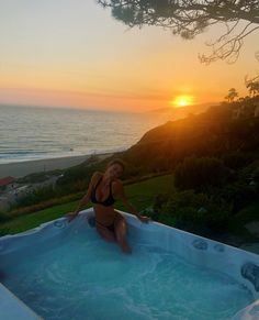 a woman sitting in an outdoor hot tub at sunset