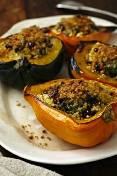 four stuffed acorn squash on a white plate with the words vegan stuffed acorn squash