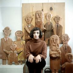 a woman sitting in front of wooden sculptures