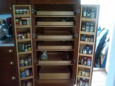 an organized pantry with wooden shelves and spice racks