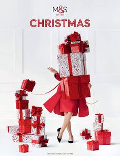 a woman in a red dress is pulling presents on a rope with her hands and the words m & s christmas written across it