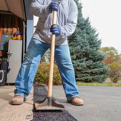 a man is holding a shovel and standing in front of a garage with gravel on the ground