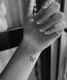 a woman's arm with a small butterfly tattoo on the left wrist and an arrow in the middle