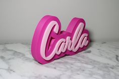 a pink sign that says cabla on top of a marble countertop in front of a gray wall