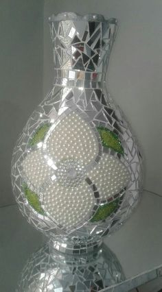 a glass vase with white and green designs on the top is sitting on a table