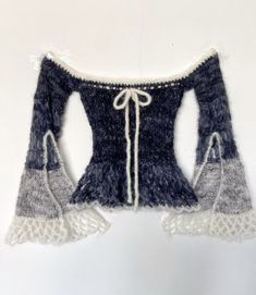 an off - the - shoulder sweater with crochet laces is hanging on a wall