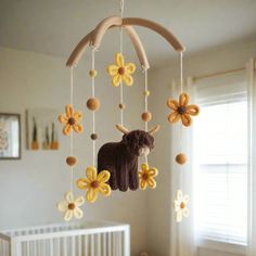 a crib mobile with a cow and flowers hanging from it's sides in a nursery room