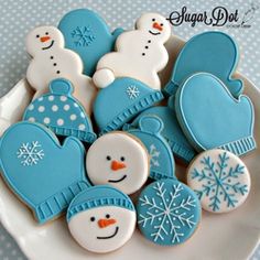 decorated cookies in the shape of snowmen and mittens are on a white plate