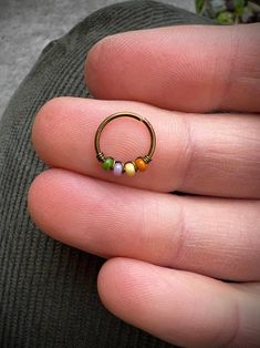 a person's hand holding a gold ring with three beads on the inside of it