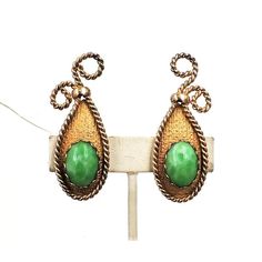 This is part of Chairish’s Costume Jewelry assortment.  1950s goldtone hatched and wire rope design with cabochon faux-jade clip back earrings. Marked "Napier." Measure: 2 1/4 inches long by 7/8 inches wide. Condition: Very good; some metal wear. Earrings like these with faux-carnelian are shown on pg 279 of Melinda L. Lewis & Henry Swen's book "The Napier Co.: Defining 20th Century American Costume Jewelry."  Please reference the measurements noted in the description above for the best approxim Vintage Metal Cabochon Earrings, Vintage Cabochon Metal Earrings, Vintage Green Cabochon Earrings, Rope Design, Accessories Jewelry Earrings, Modern Branding, Vintage 1950s, Costume Jewelry, Clip On Earrings