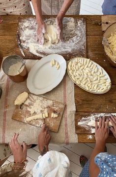 several people are making pizza dough on a table