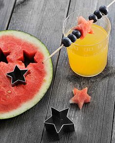 a watermelon slice with black stars on it next to a glass of orange juice