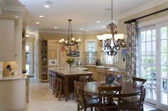 a large kitchen with an island and dining table in the center, surrounded by windows