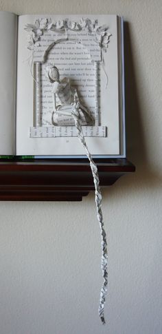 an open book with a string attached to it on a shelf next to a wall