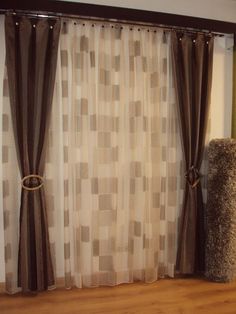 a cat scratching post in front of a window with curtains and rugs on the floor