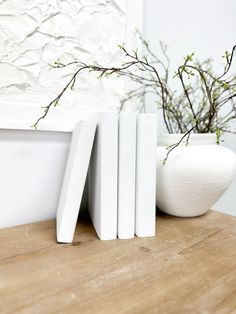 three white bookends sitting on top of a wooden table next to a vase