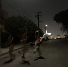 three people are running in the street at night