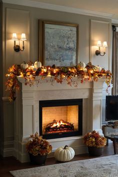 a living room filled with furniture and a fire place covered in fall leaves on top of a mantel