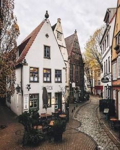 a cobblestone street in an old european town with white buildings and brick streets