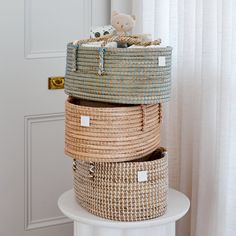 three wicker baskets stacked on top of each other in front of a white door