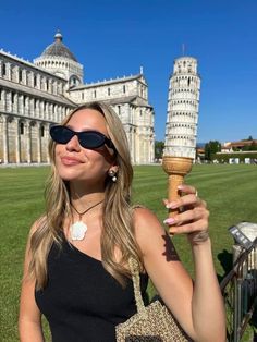 a woman holding an ice cream cone in front of the leaning tower of pisa