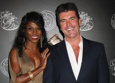 a man and woman standing next to each other in front of a red carpeted wall