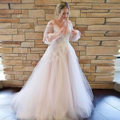 a woman in a wedding dress standing next to a brick wall with her hands on her hips