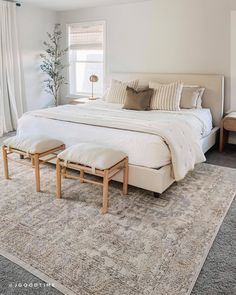 a large bed sitting on top of a rug in a bedroom next to a window