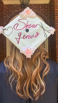 a woman wearing a white graduation cap with pink flowers on it and the words shear genius