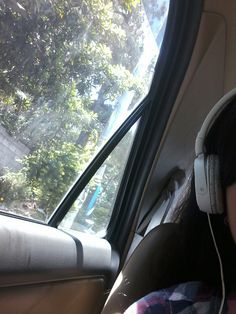 a woman wearing headphones sitting in the back seat of a car