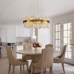 a dining room table with chairs and a chandelier hanging from it's ceiling