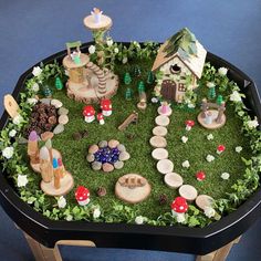 a black tray filled with lots of different types of toys and decorations on top of green grass