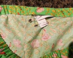 the bottom of a green skirt with pink flowers on it and a pair of scissors