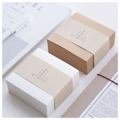 two boxes sitting on top of a table next to papers and glasses with writing paper